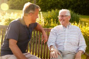 A diverse group of older adults sitting together and smiling in a comfortable communal lounge.