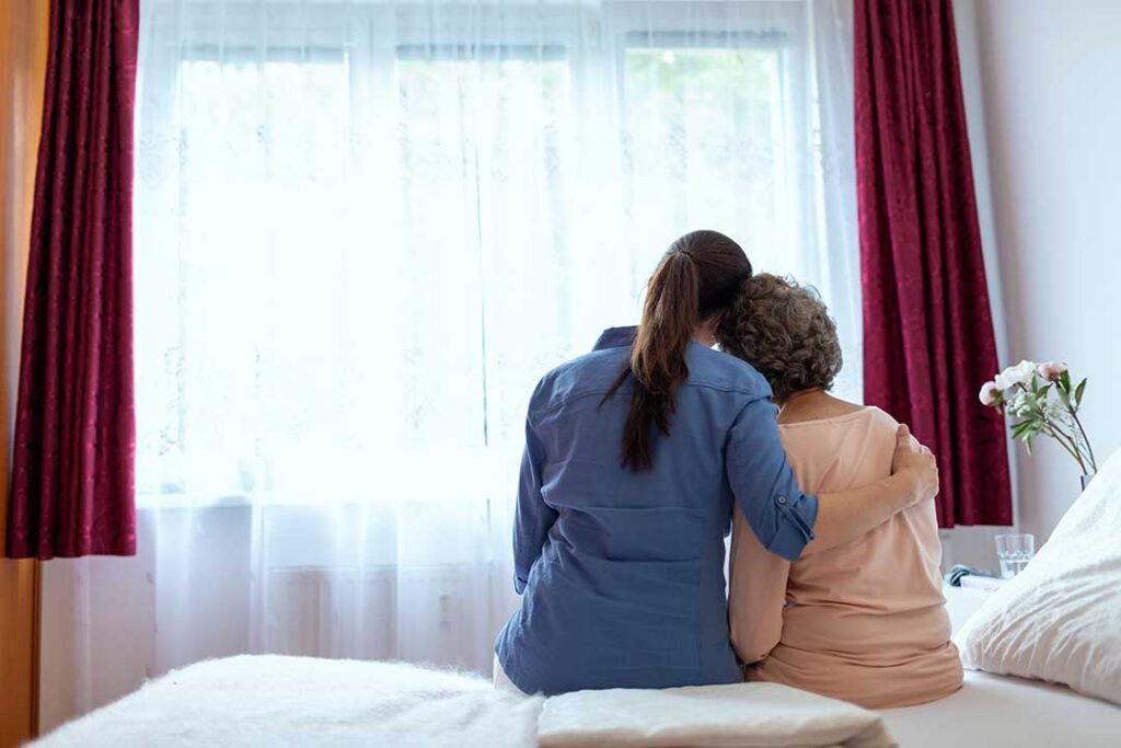 Family member and older adult participating in a seated music activity in an assisted living common room.